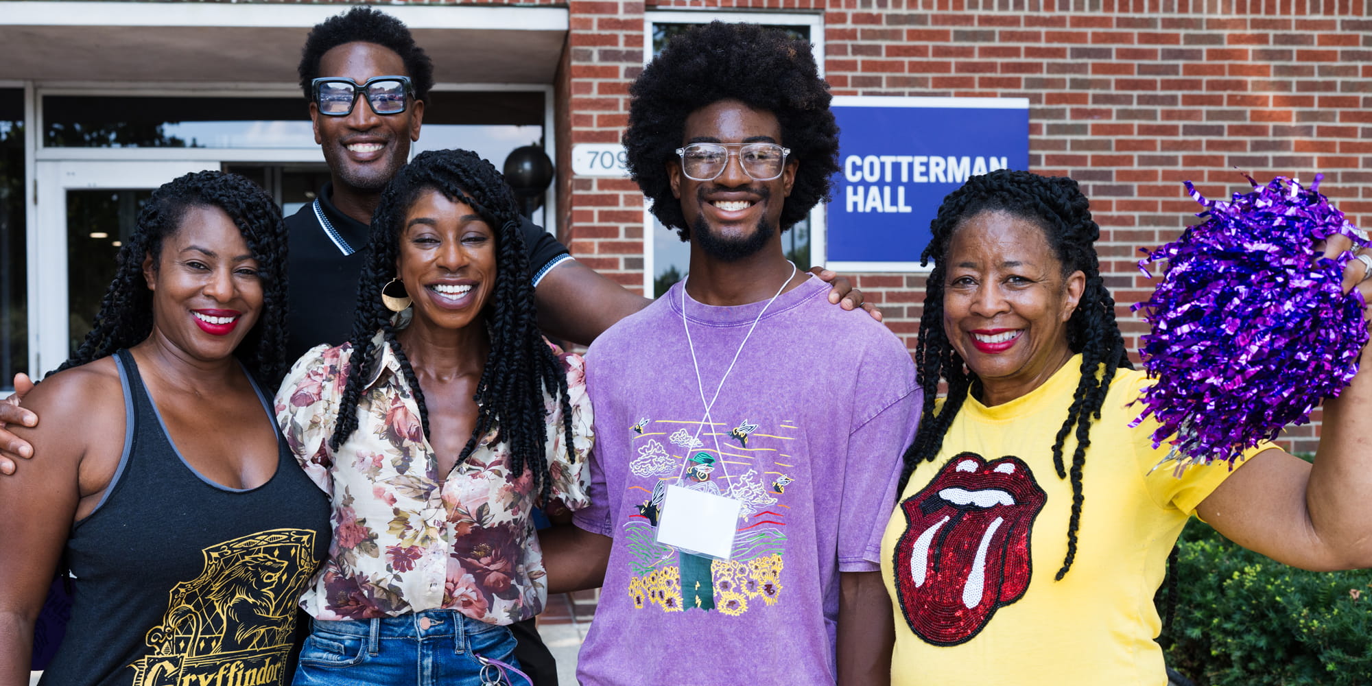 A happy family poses for a photo outside of Cotterman Hall