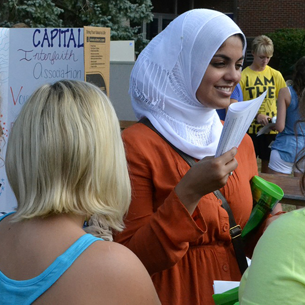 An international student provides information at a booth during Capital's welcome weekend
