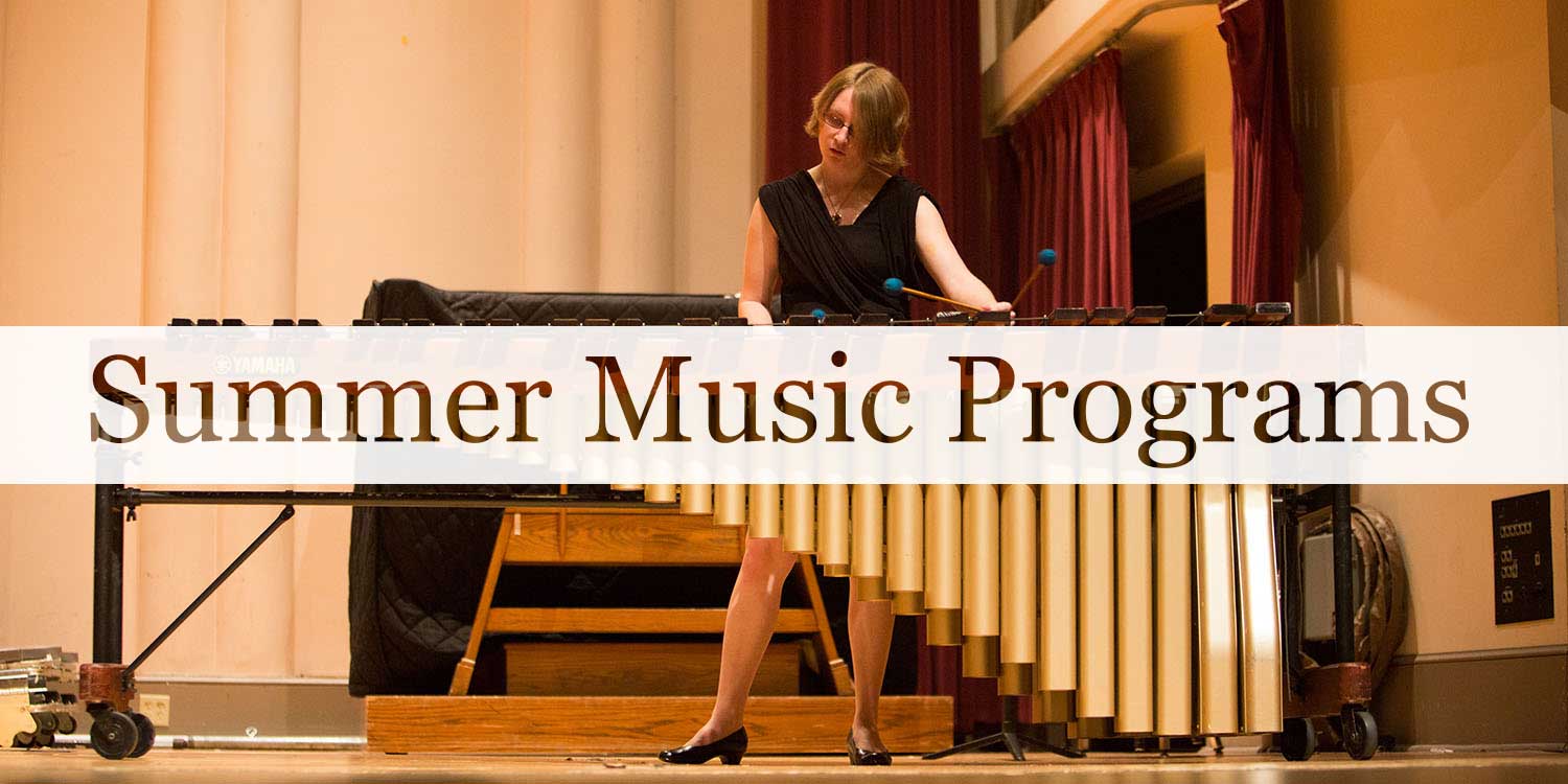 Young woman in black dress with short brown hair and glasses playing musical instrument