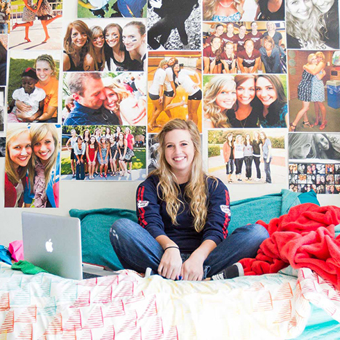 Student in dorm room sitting on her bed