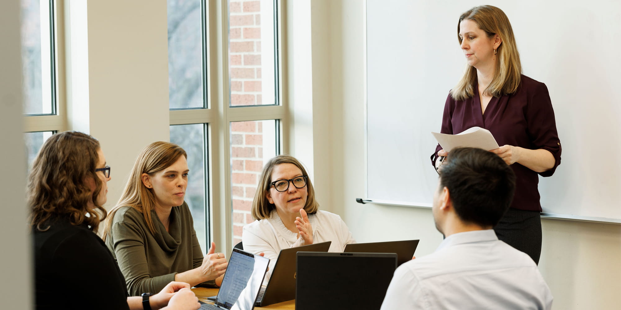 Faculty and students meeting by a window