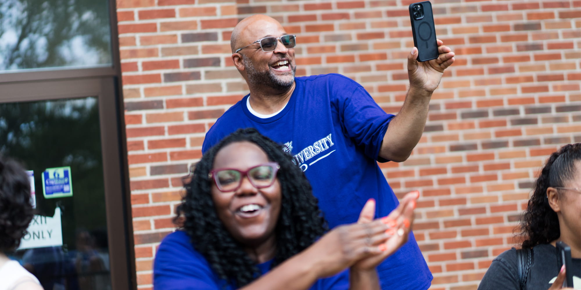 A dad smiles while taking a photo with his phone